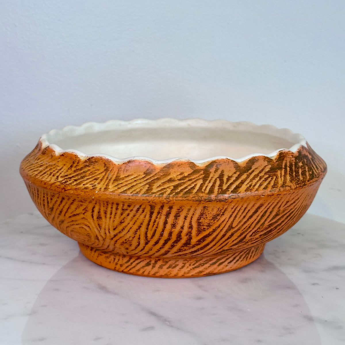 A round ceramic planter bowl with a textured orange-brown exterior and a white interior, sitting on a white marble surface against a light blue-gray wall., photo 2