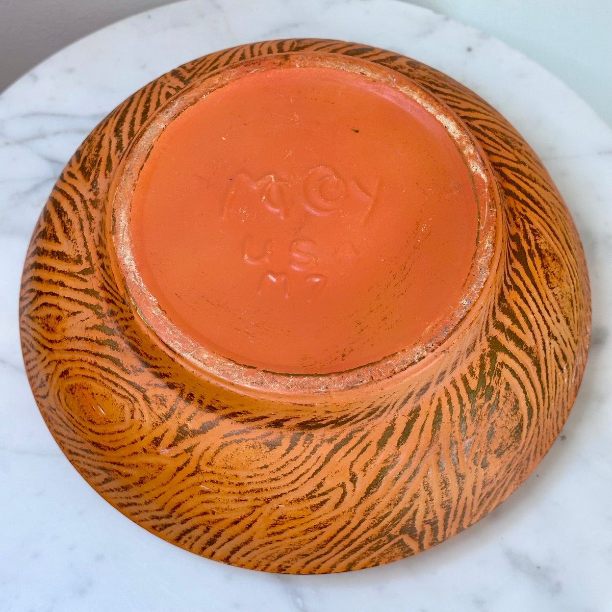 An upside-down ceramic bowl with a textured orange-brown patterned exterior and a smooth terracotta-colored interior, showing the embossed brand name 'McCoy USA M7' on the bottom, set on a white marble surface., photo 7