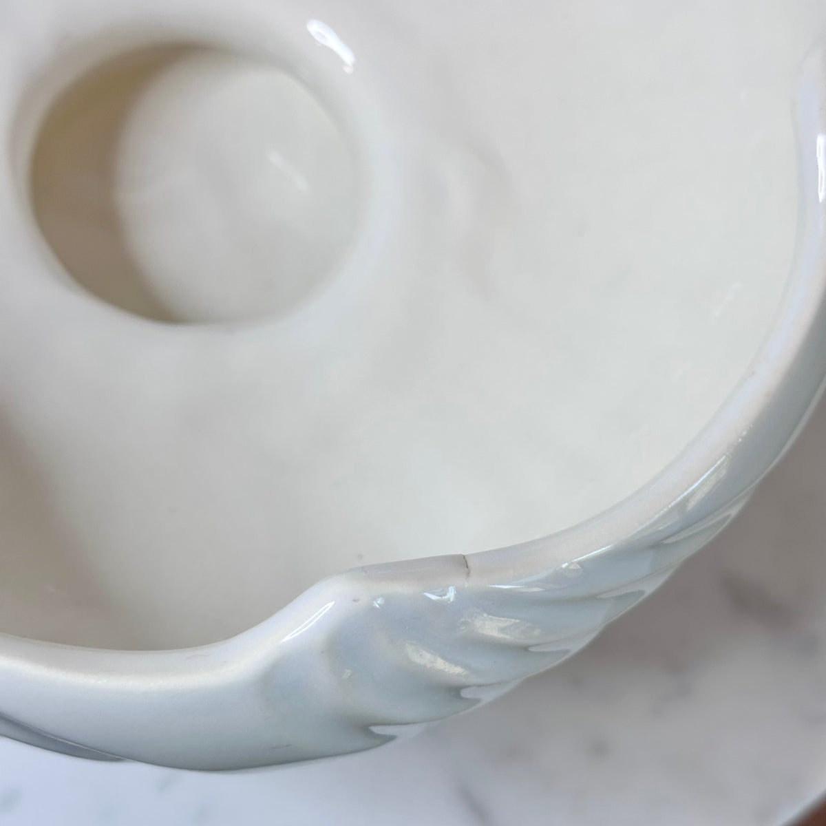 A glossy white ceramic pedestal bowl with a fluted, ribbed exterior and wavy rim, displayed on a white marble surface against a light gray background., photo 3