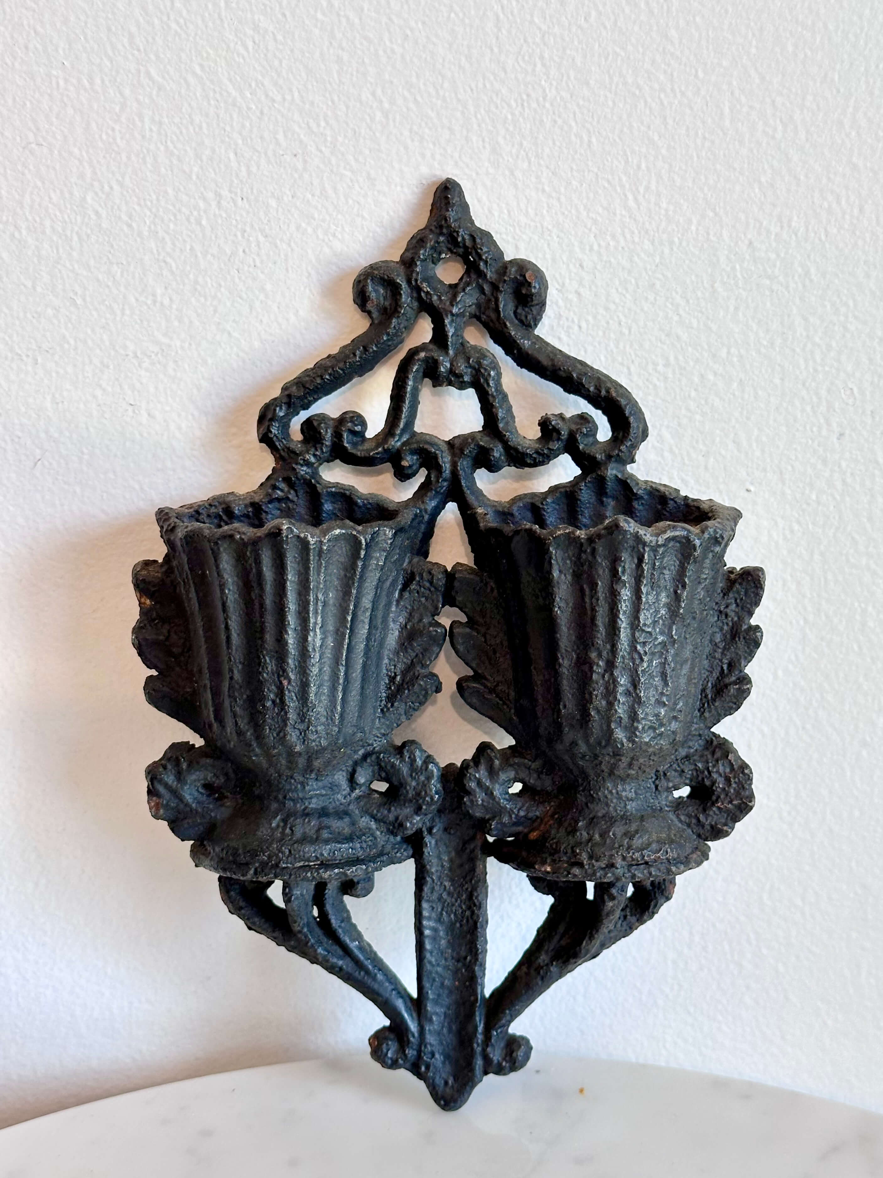 An antique black cast iron double urn match safe with black scroll work and striking plate down the center.