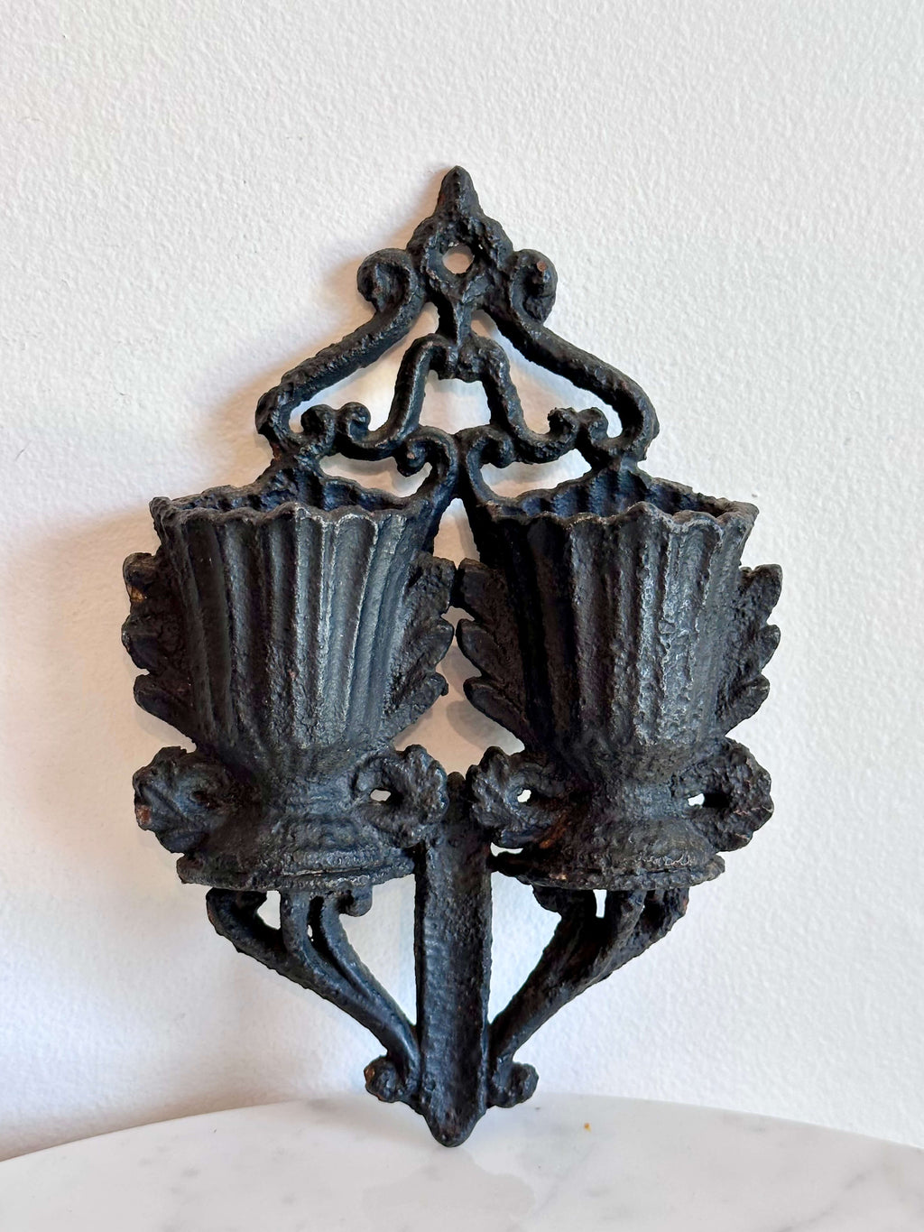 An antique black cast iron double urn match safe with black scroll work and striking plate down the center.
