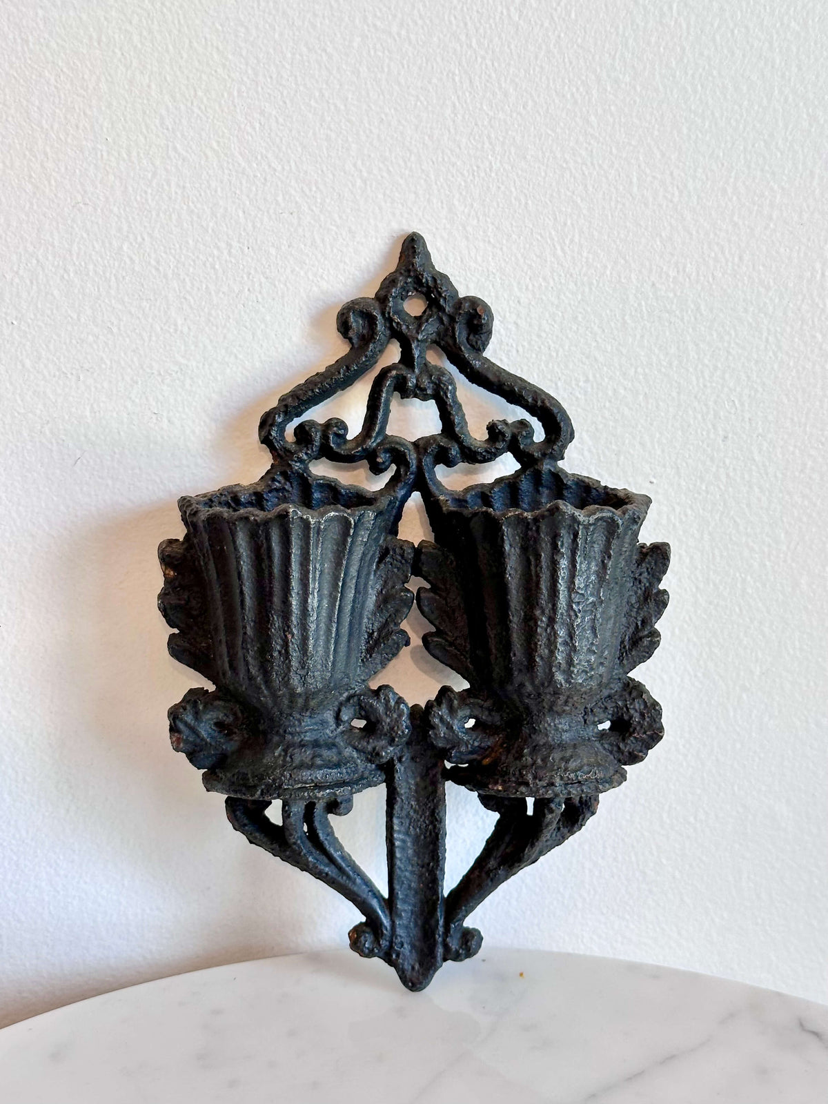 An antique black cast iron double urn match safe with black scroll work and striking plate down the center.