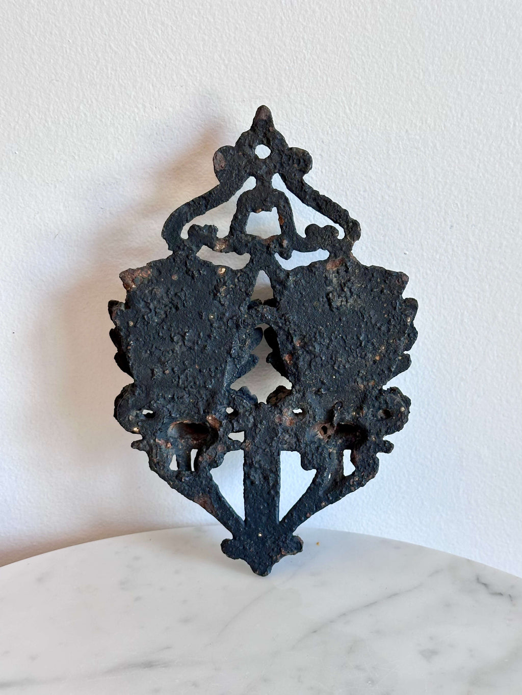 Back side of an antique black cast iron double urn match safe with black scroll work and striking plate down the center.