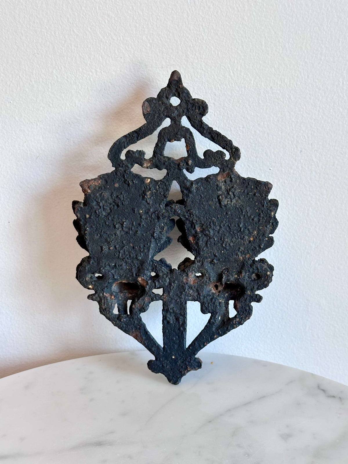 Back side of an antique black cast iron double urn match safe with black scroll work and striking plate down the center.