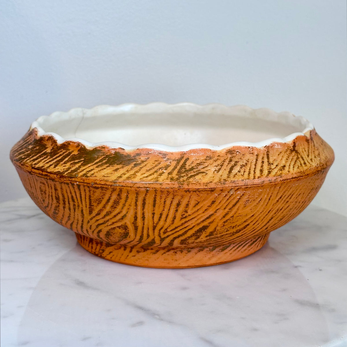 A round ceramic planter bowl with a textured orange-brown exterior and a white interior, sitting on a white marble surface against a white wall., photo 6