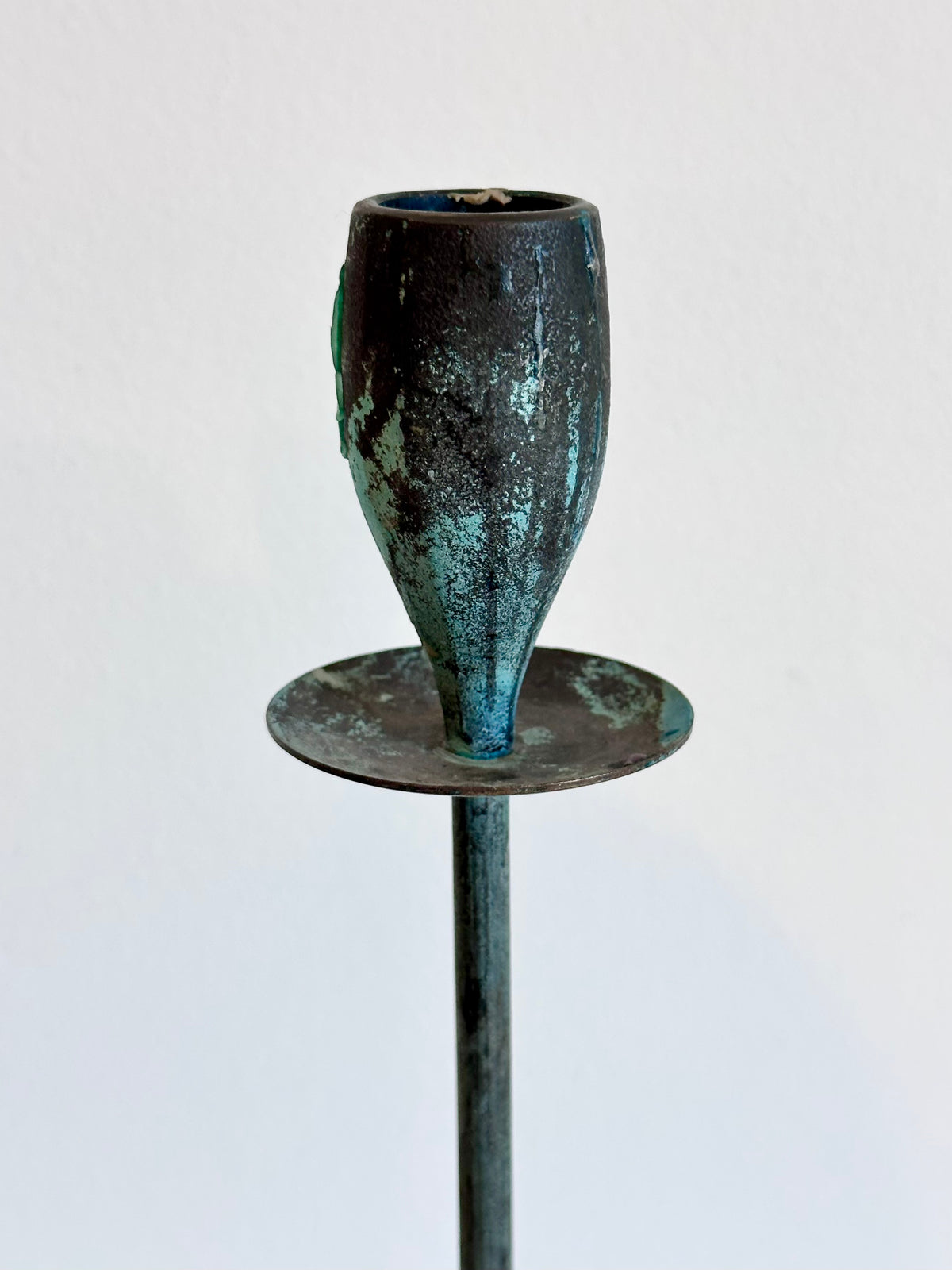A vintage-style metal candlestick holder with a textured, verdigris-covered dark body and a round base, mounted on a vertical stem against a plain white background., photo 4