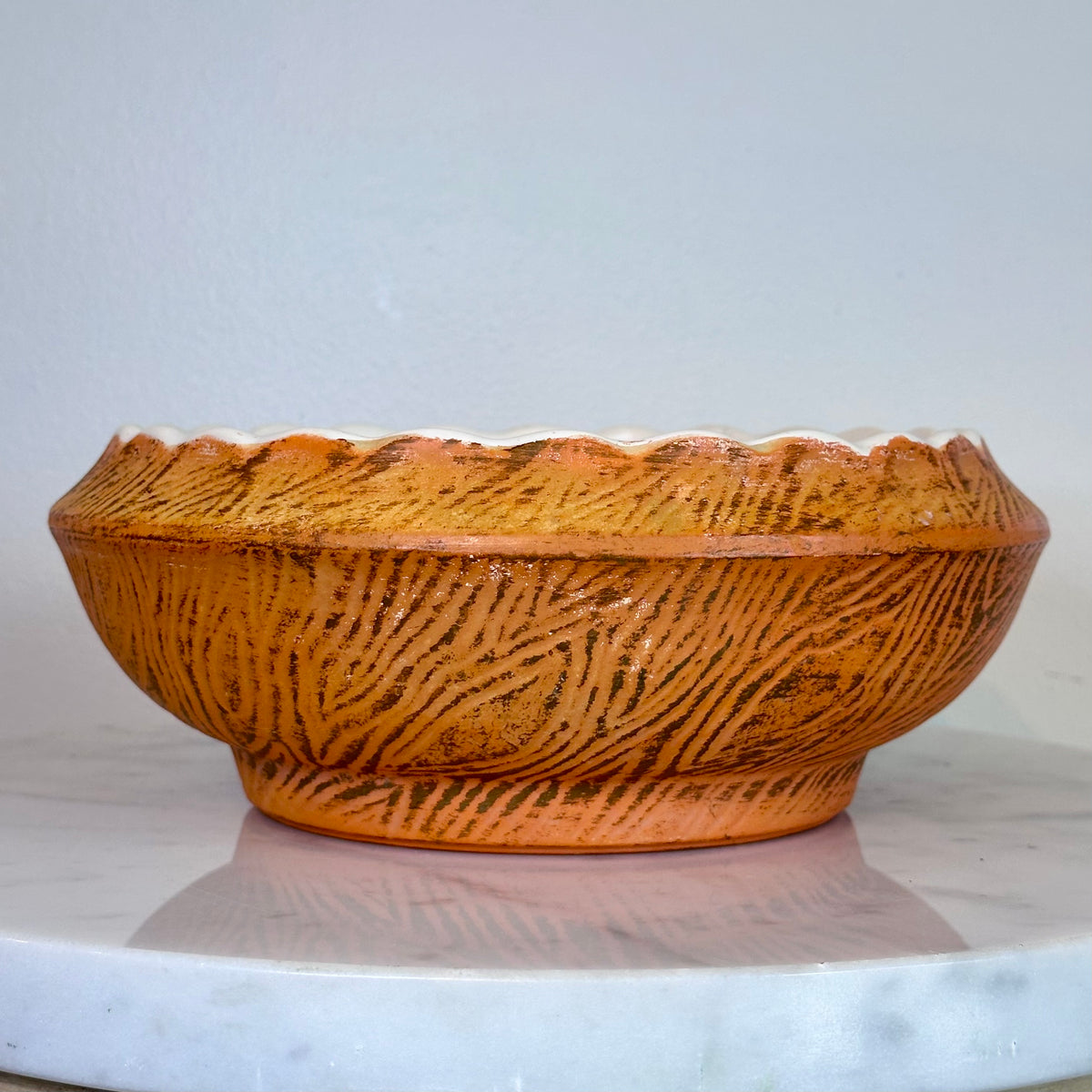 A round ceramic planter bowl with a textured orange-brown exterior and a white interior, sitting on a white marble surface against a light blue-gray wall., photo 5