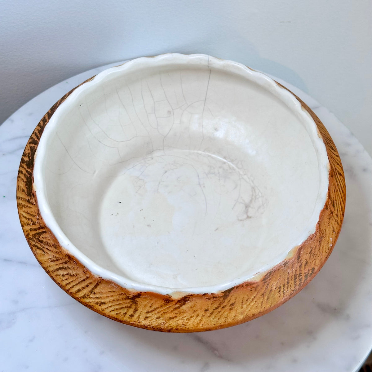 A handmade ceramic bowl with a glossy white interior and a textured, earthy brown exterior, displayed on a white marble surface., photo 4