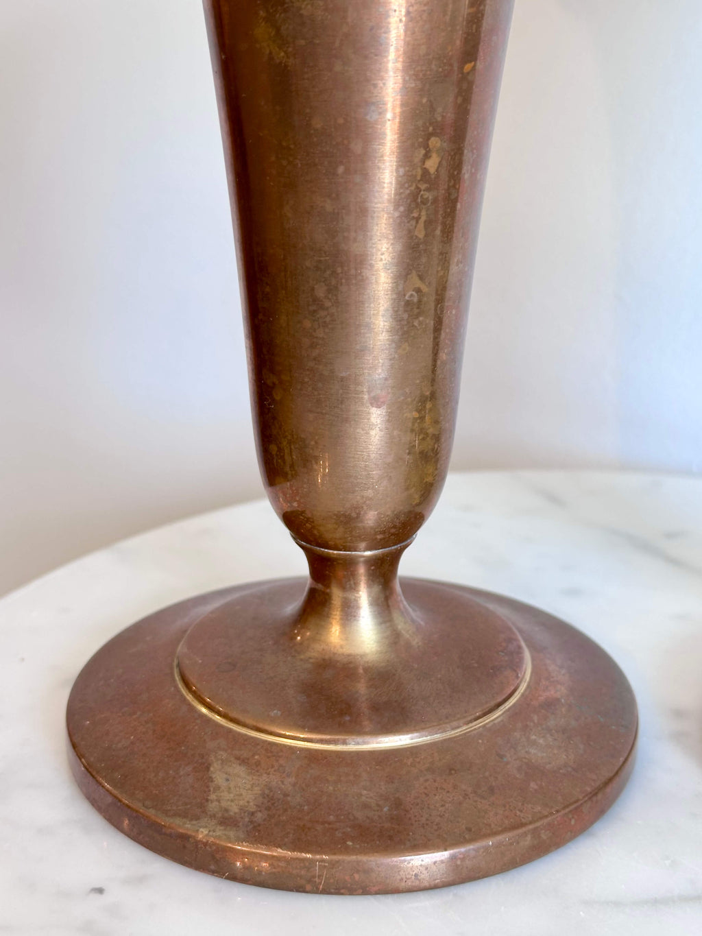 Close up of Vintage Brass Trumpet Style Church Altar Vase displayed on a white marble surface against a plain white wall.