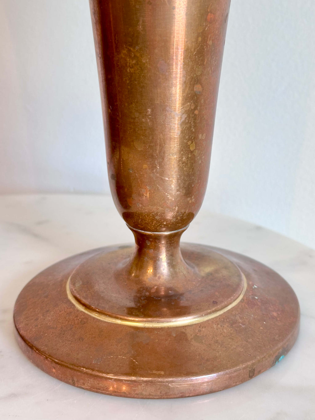 Close up of Vintage Brass Trumpet Style Church Altar Vase displayed on a white marble surface against a plain white wall.