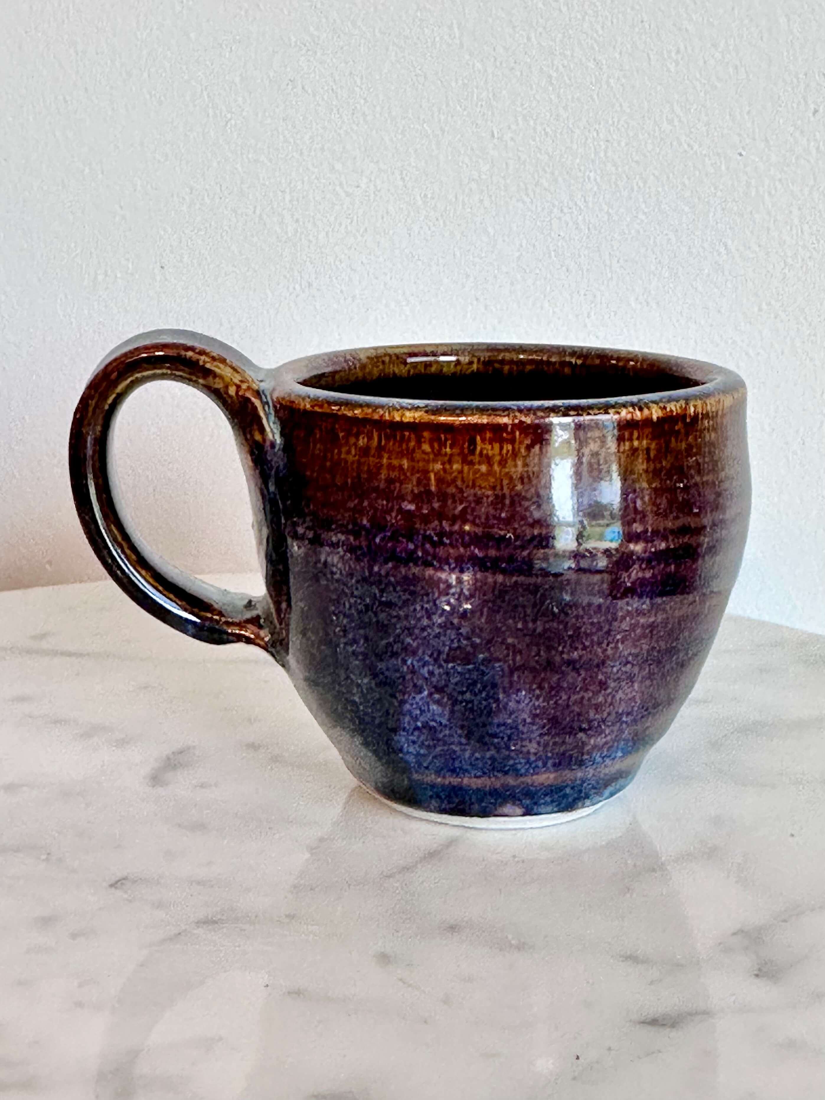 a handmade ceramic coffee mug with a blue purple drip glaze